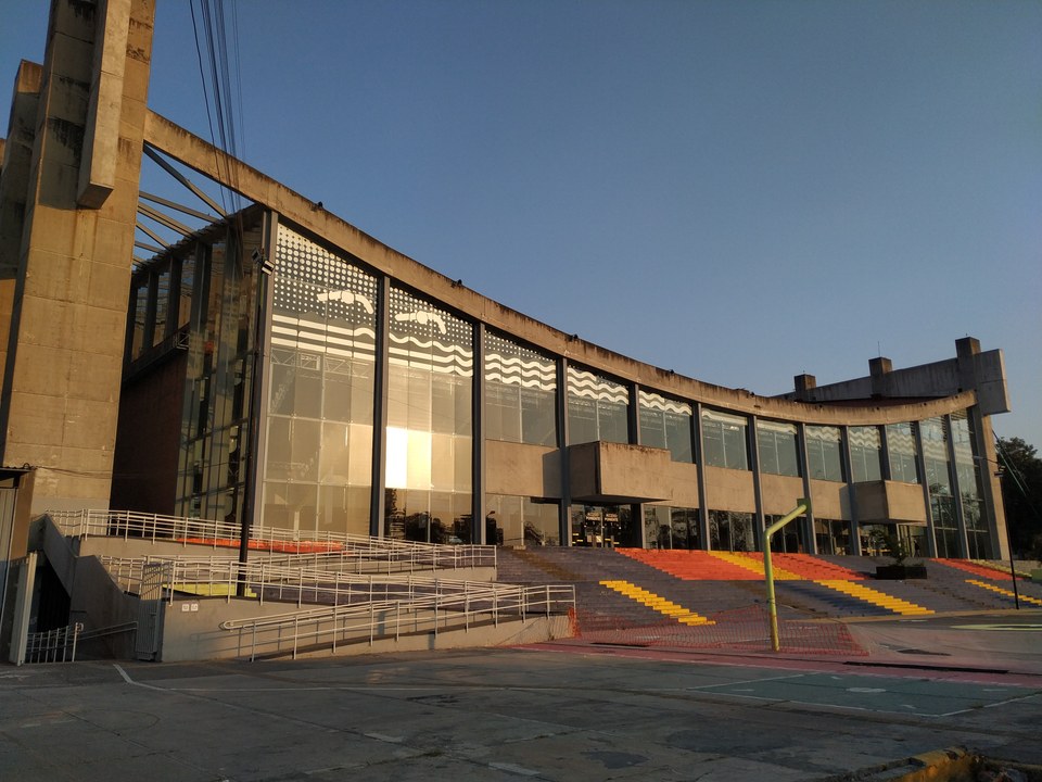 A modern concrete and glass building with large windows, colorful steps, and accessibility ramps.